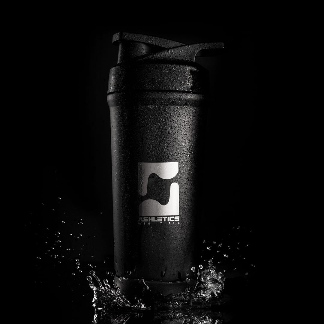 Shaker-cup-black-background Black shaker cup with silver logo splashing into water in shadow on a pitch black background